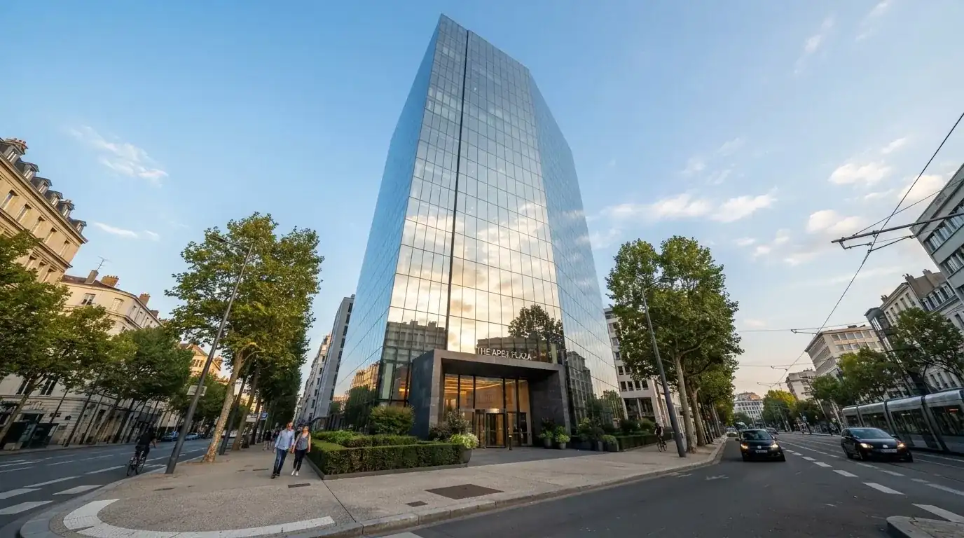 Un edificio de oficinas con fachada de cristal reflejando el cielo, fotografiado desde la acera de una calle ancha.